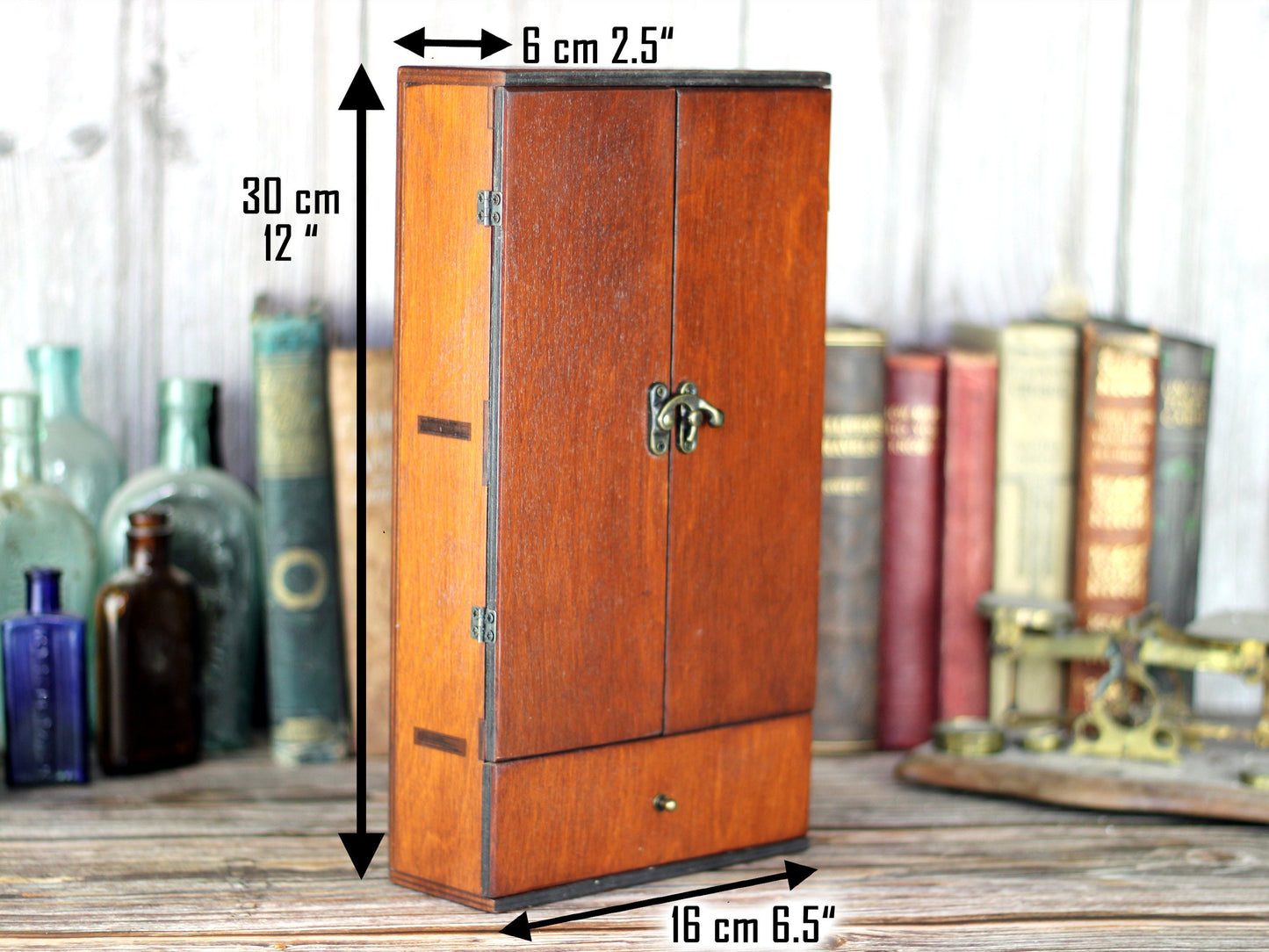 Wooden apothecary cabinet with skull engraving and poison drawer holds six brown medicine bottles with glass stoppers