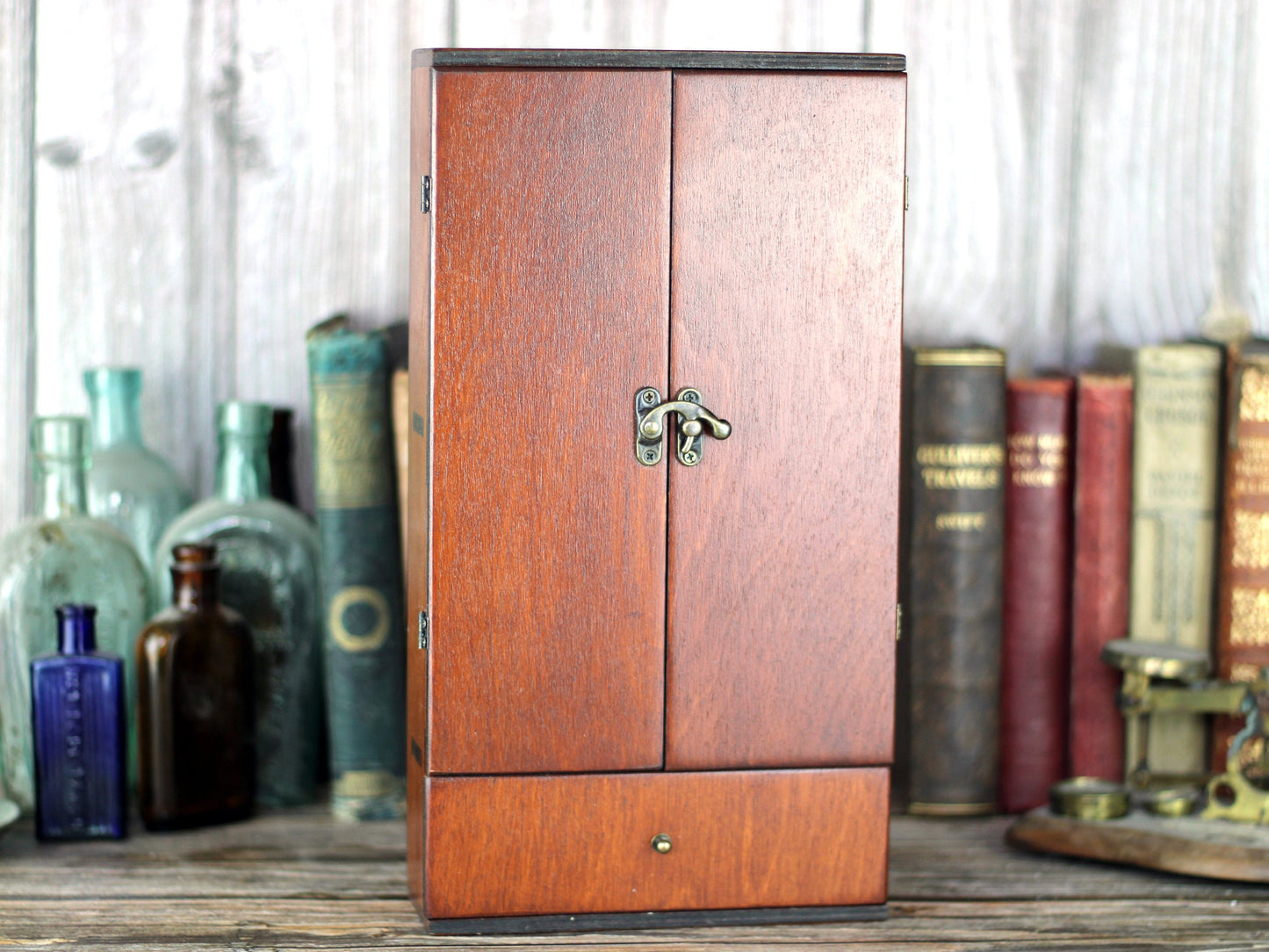 Wooden apothecary cabinet with drawer and holding six brown medicine bottles with glass stoppers