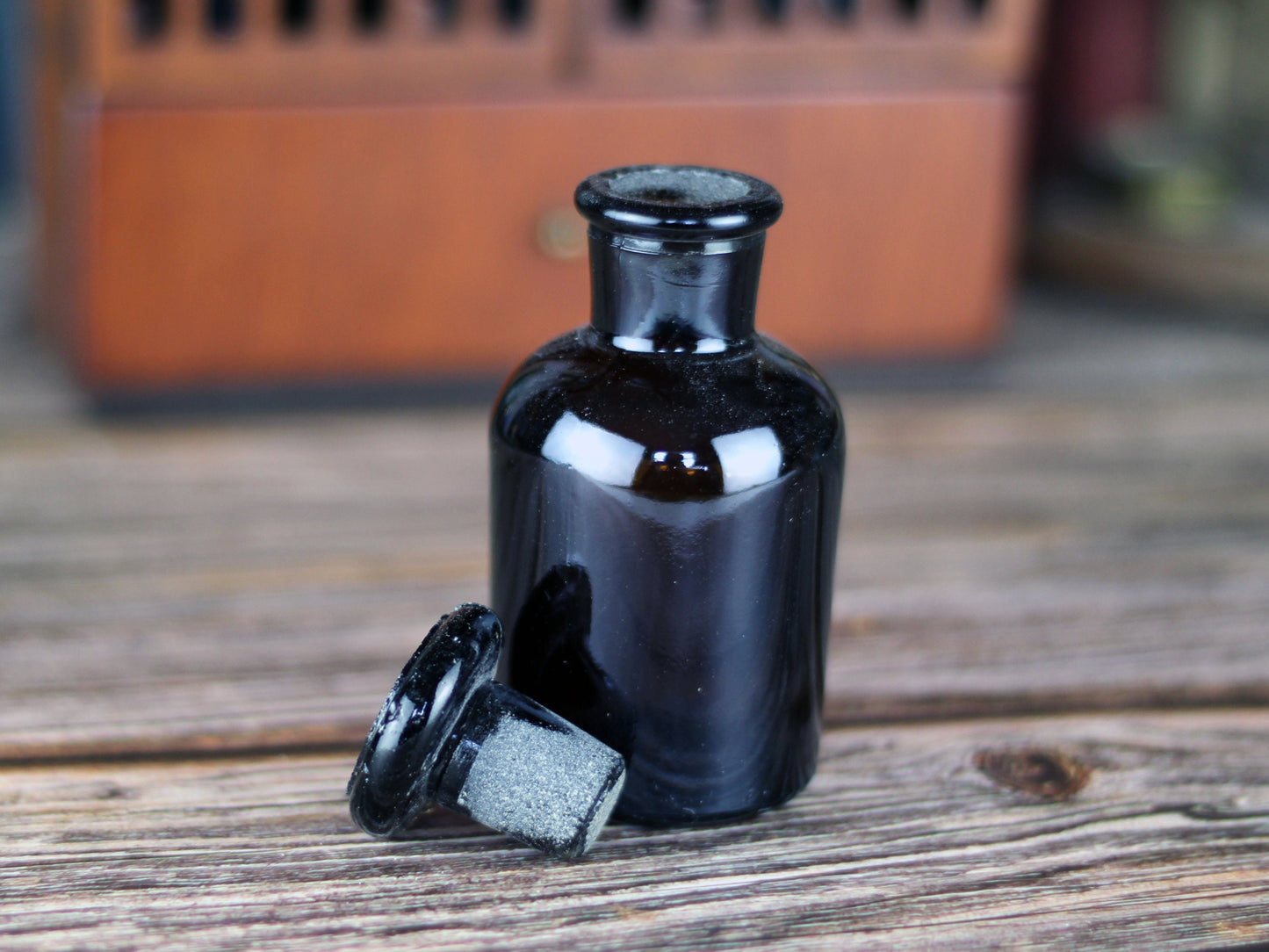 Wooden apothecary cabinet with slatted doors, drawer and 6 brown medicine bottles with glass stoppers